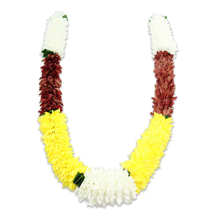 Set against a pristine white field that allows every hue to sing, this U-shaped ceremonial garland reads like a small, portable altar. Its craftsmanship is immediately apparent: each arm starts at the top with a thick, cylindrical section of creamy white blooms - tiny chrysanthemum-like fabric petals layered so densely they appear almost tactile, like a soft textile you could rest your palm upon. Below this serene white sits a deep maroon or reddish-brown band, the saturated tone bringing an earthy counterpoint and visual weight through carefully arranged, minute petals. The garland's principal sweep is a long, bright yellow segment; these cheerful, marigold-like flowers are plush and abundant, forming the broad curve of the 'U' and bathing the piece in warmth. At the base where the arms meet, a larger, lush cluster of white chrysanthemum-style flowers provides a striking focal point, while small, dark green leaf accents are placed thoughtfully at the colour joins - notably between yellow and white - to offer natural contrast and definition. The synthetic construction is deliberate: thousands of fabric petals are stitched and arranged to emulate the look and fullness of fresh garlands, made to endure processions, temple offerings, weddings and festival rituals. In Cheam village contexts - community pujas near the high street or private ceremonies close to Cheam station and the green spaces around Nonsuch Park - such a mala carries both visible beauty and cultural resonance. It reads as respectful, celebratory and expertly assembled, the colours symbolising purity, prosperity and devotion while the hand-worked texture testifies to a florist's quiet skill.