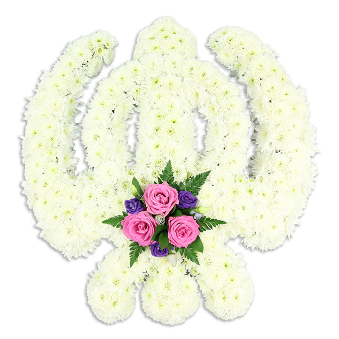 This image presents a beautifully detailed Sikh Khanda floral tribute, carefully constructed from a blanket of white blossoms and displayed against a spotless white backdrop. The sacred Khanda symbol is instantly recognisable: a central, upright double-edged sword flanked by a smooth circular chakkar and two gracefully arched kirpans crossing outward at the base. Each element is formed from tightly massed chrysanthemum-like flowers in clean white and soft cream shades, their small petals overlapping to create a plush, cushion-like surface. The flowers sit so close together that no gaps of greenery show through, giving the piece an almost carved appearance, as if a single block of blooms has been shaped into the emblem. At the bottom centre, where the curved swords nearly meet, a contrasting cluster of colour adds warmth and tenderness. Three pink roses sit prominently, their petals layered and velvety, flanked by smaller, deep purple flowers that bring a more solemn richness to the palette. Fresh fern fronds and other green foliage peek between the blooms, creating a natural frame that softens the strong geometric lines of the Khanda. Subtle, even lighting casts a gentle shadow beneath the arrangement, suggesting depth and making the floral work feel ready to be carried into a Gurdwara or funeral chapel in Cheam, perhaps near the quiet residential streets and parks that define the area. This tribute feels particularly suited to a Sikh funeral or memorial service, where families wish to honour both faith and tradition through a floral symbol that reflects their loved one's devotion and the calm strength of their community.