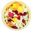 In this overhead image, a softly rounded, pale yellow stoneware-style bowl is completely filled with loose petals, creating an intimate and gentle floral display that feels perfectly suited to a funeral tribute or memorial gathering in Cheam. The petals are predominantly from roses, their shapes broad and slightly cupped, forming layers of crimson red, golden yellow, and soft peachy orange. Each petal seems to rest naturally where it has fallen, some edges curling slightly, others lying smooth and open, giving the surface of the bowl a rippling, quilt-like appearance. Among these richer tones are numerous small, white hydrangea florets, their many tiny petals forming clusters that look almost cloud-like against the stronger colours. The hydrangea brings a whisper of light and purity to the composition, softening the deeper reds and warm yellows and suggesting a balance between grief and gratitude. The lighting is bright but gentle, with no harsh shadows, allowing the interplay of colour and texture to show through clearly: the matte, almost silky surface of each rose petal; the more papery, fragile feel of the hydrangea blossoms. This is the kind of petal bowl you might find on a remembrance table at a service near Cheam's quiet residential streets, inviting mourners to pause, touch, and remember. It evokes the idea of scattering petals at a graveside or placing them beside a candle, each small gesture carrying a message of love, respect, and a peaceful final farewell.