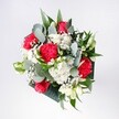 This hand-tied bouquet feels like a bright Cheam morning captured in flowers, laid out as if on a sunlit kitchen table near the village crossroads. Deep red roses with velvety, tightly swirled petals form the confident heart of the arrangement, their rich colour echoed by ruffled pink-red carnations that look almost feathery at the edges. Around them, small, snow-white daisies and clustered white chrysanthemums open like tiny suns, their soft, daisy-centre eyes creating a gentle halo that lightens the whole design. Wisps of cloudlike gypsophila thread delicately between the blooms, catching the light and giving the bouquet a softly sparkling, celebratory feel. Cool eucalyptus, with its silvery-green, rounded leaves, curls gracefully outwards, mingling with deeper tropical foliage to frame the flowers in a modern, stylish way without stealing the focus. The mix of glossy and matte greens adds texture and depth, making the reds and whites appear even more vivid. The bouquet is compact yet airy, each stem placed with the kind of quiet precision you'd expect from an experienced local florist who knows exactly how Cheam families like their flowers for birthdays, homecomings, and quiet congratulations. You can almost sense the faint, herbal scent of eucalyptus mingling with the sweetness of rose and the freshness of chrysanthemum, like walking through a garden after rain in nearby Nonsuch Park. The mood is optimistic, warm, and welcoming - a bouquet designed to mark heartfelt moments, brighten a favourite corner, or greet someone at the door with a burst of colour and comforting, familiar fragrance.